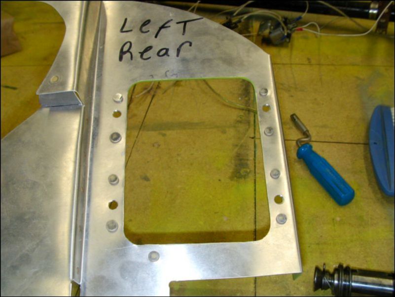 Cut oil cooler hole in left rear engine baffle.  Deburr, clean, prime, and solid rivet the oil cooler mounting ring to the baffle.