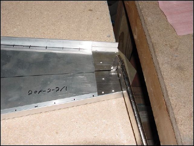 Another view of the lower bottom rudder hinge, shim, lower top rudder hinge, and lower rear longerons clamped into position on the top of the bottom skin.