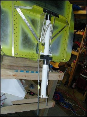 Now for the fun part.  I have no idea if this is how you should do this, but it worked for me.  I put the bungee pin in place and then bent a U clamp so that I could slide it through the pin.  Then I bent it back down and connect threaded rod to it.  Then Lubricate the top end of the nose gear and the lower bearing.  Position the bungee and slide the nose gear leg into place.  Then I put a bar under the nose gear with the threaded rod through this bar and placed nuts on the threaded bar.  Then I was able to slowly tighten the nuts to press the strut in place.  Once in place I installed the bolts for the lower bearing and also the nose gear top plate and castle nut.  I hope this helps a few builders out there.