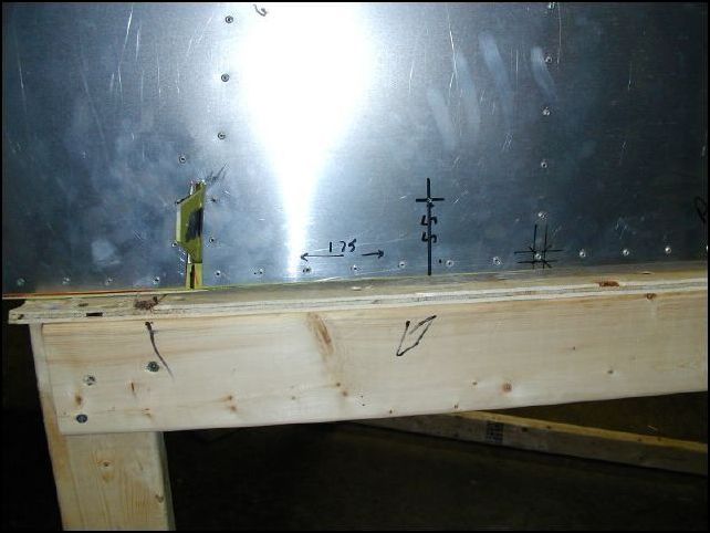 Measure back from the rear channel (rear wing pickup) 175 mm.  Measure up 55 mm plus the thickness of the lower longeron.  This is about 58 mm from the bottom of the fuselage.