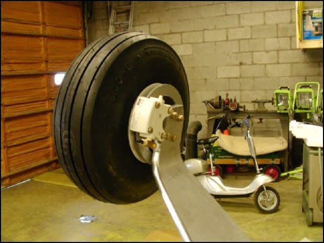 Again, I should have taken more pictures of this process, however what you do now is to position the main gear axel to the landing gear and drill the four bolt holes.  Then slide the brake caliper bracket on to the axel and bolt the axel to the main gear.  Install the tire and brake caliper, cotter pin the axel nut in place and install the hub caps.