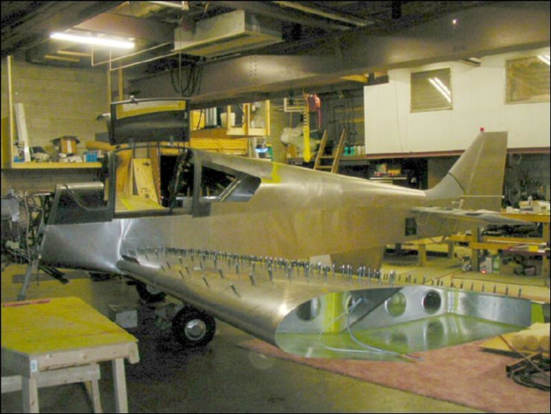 Deburr, clean, prime, and rivet the flap to the wing.  Deburr, clean, and prime all top skins.  Trim inboard skin to fit the shape of the fuselage.  Drill holes in side of fuselage for wires, pitot, static, and control cables.  Bolt wing to aircraft!